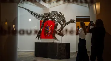 Pengunjung melihat kerangka Barry, spesimen besar Camptosaurus dari akhir periode Jurassic, yang dipajang sebelum dilelang di galeri Georges-Philippe & Nathalie Vallois, Paris, Senin (18/9/2023). (Dimitar DILKOFF / AFP)