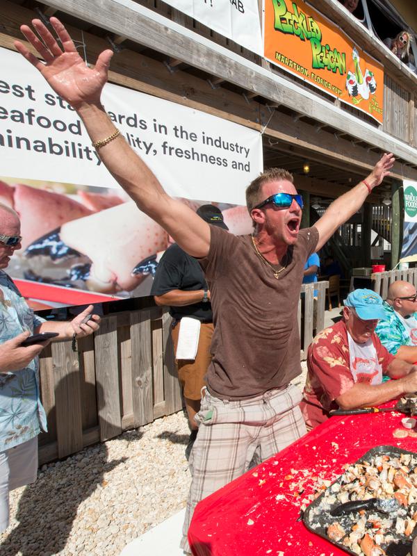 Christian Gatti berselebrasi setelah memenangkan kontes Key Fisheries Stone Crab Eating di Marathon, Florida, Sabtu (10/11). Para peserta beradu cepat memecahkan cangkang 25 kepiting batu lalu memakan dagingnya. (Andy Newman/Florida Keys News Bureau/AFP)