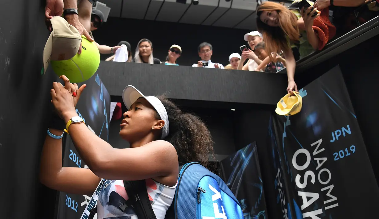 Petenis Jepang Naomi Osaka menandatangani benda yang disodorkan penonton usai mengalahkan petenis Republik Ceko Marie Bouzkova pada Australia Terbuka di Melbourne, Australia, Senin (20/1/2020). Penonton menyodorkan topi, bendera, hingga bola untuk ditandatangani Naomi. (AP Photo/Andy Brownbill)