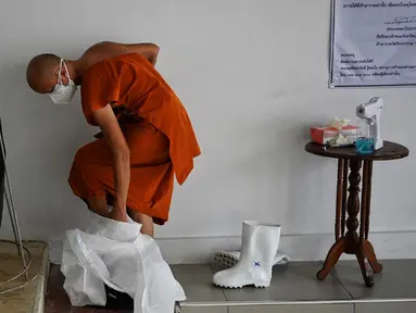 Seorang biksu melepas alat pelindung diri setelah melakukan kremasi untuk korban virus corona COVID-19 di Wat Chin Wararam Worawihan, Bangkok, Thailand, 30 Juli 2021. Kasus COVID-19 di Thailand kini tengah melonjak. (Lillian SUWANRUMPHA/AFP)