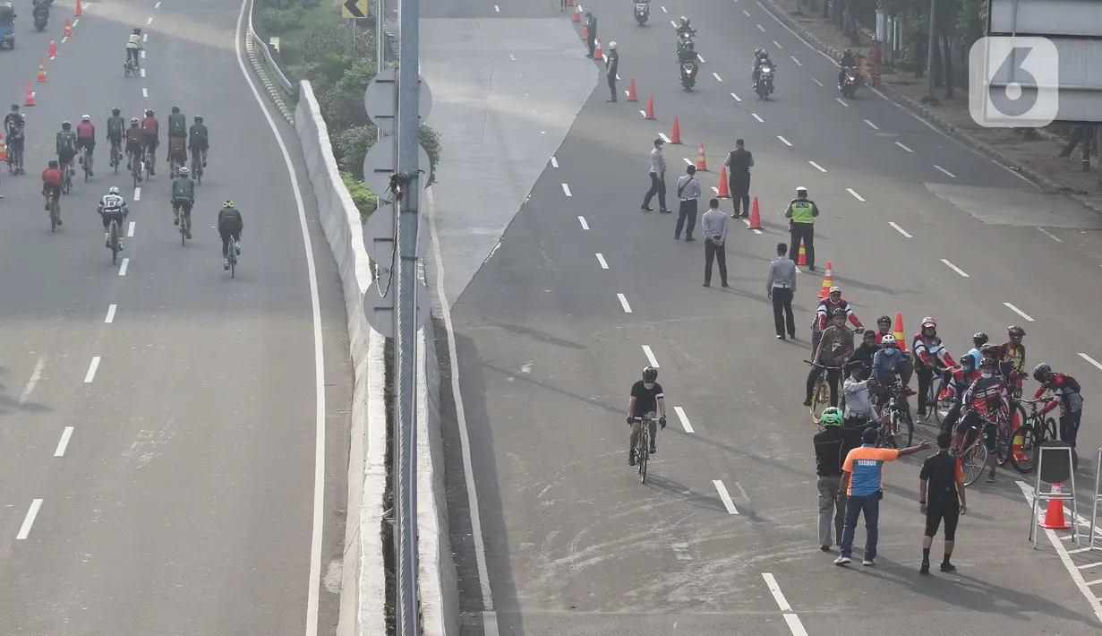 Petugas mengarahakan pesepeda non road bike saat memasuki JLNT Kampung Melayu-Tanah Abang, Jakarta, Minggu (30/5/2021). Uji coba kedua ini bertujuan kembali mendapatkan masukan dari penggiat sepeda secara lengkap baik dari sisi operasional maupun teknis kedepannya. (Liputan6.com/Herman Zakharia)