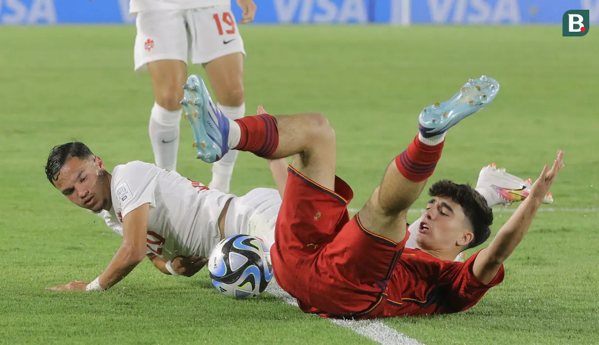 <p>Pemain Timnas Spanyol U-17, Peio Huestamendia (kanan) berebut bola dengan pemain Kanada U-17, Lino Aklil dalam pertandingan babak penyisihan Grup B Piala Dunia U-17 di Stadion Manahan, Solo, Jumat (10/11/2023). (Bola.com/Arief Bagus)</p>