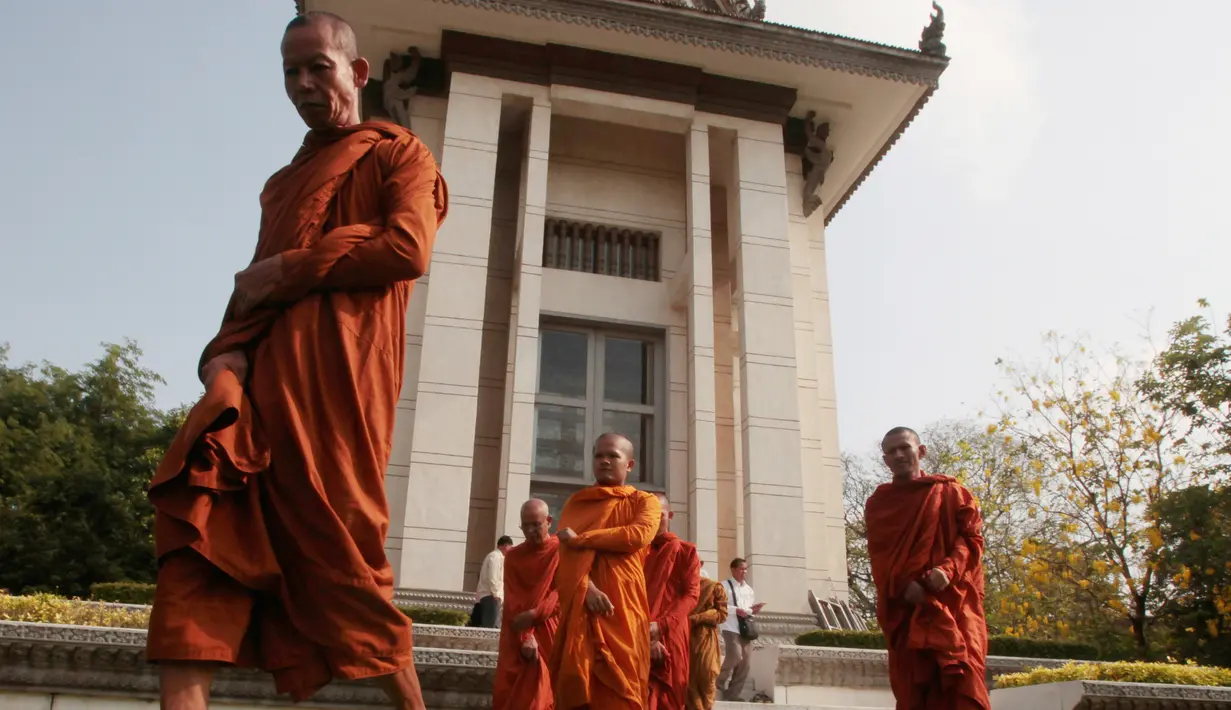 Biksu meninggalkan stupa yang berisi ratusan tengkorak dan tulang korban rezim Khmer Merah usai berdoa di Choeung Ek memorial, Kamboja (17/4). Mereka berdoa untuk memperingati 42 tahun jatuhnya rezim Khmer Merah pimpinan Pol Pot. (AP Photo/Heng Sinith)