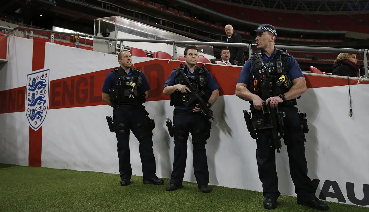 Kepolisian Inggris dengan senjata lengkap menjaga latihan timnas Prancis jelang laga ujicoba melawan Inggris di Stadion Wembley, Inggris, Senin (16/11/2015). (AFP Photo/Adrian Dennis)