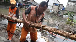 Pasukan oranye membawa kayu untuk memperbaiki tanggul yang jebol di kawasan Jatipadang, Jakarta Selatan, Selasa (12/12). Perbaikan tanggul sementara itu dilakukan dengan membuat tanggul pasir lalu menahannya dengan kayu. (Liputan6.com/Immanuel Antonius)