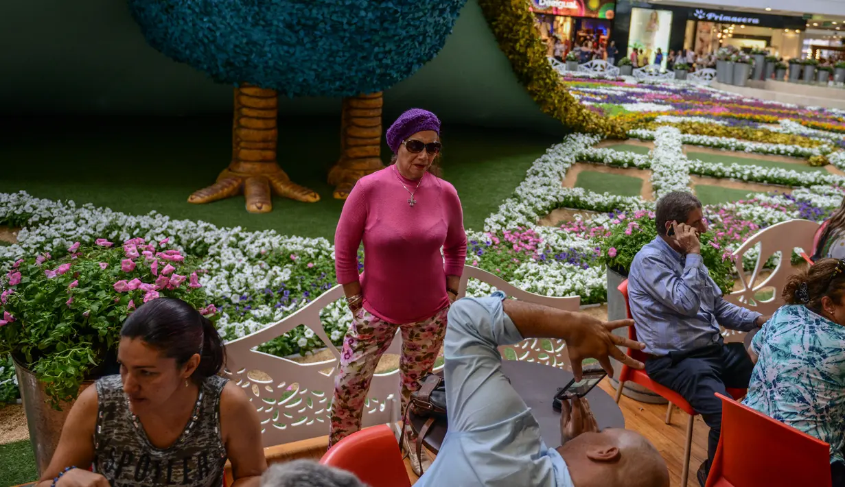 Pengunjung foto di depan merak raksasa selama Festival Bunga di Pusat Perbelanjaan Santa Fe di Medellin, Kolombia (3/8). Merak yang terbuat dari 182.000 bunga ini memiliki panjang 12 meter (40 kaki). (AFP Photo/Joaquin Sarmiento)