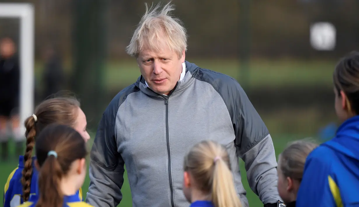 PM Inggris Boris Johnson berbincang dengan anak-anak sebelum pertandingan sepak bola putri junior antara Hazel Grove United JFC dan Poynton di Cheadle Hulme, Inggris, Sabtu (7/12/2019). Aksi itu dalam rangka kampanye jelang pemilu Inggris pada 12 Desember 2019. (Toby Melville/Pool Photo via AP)