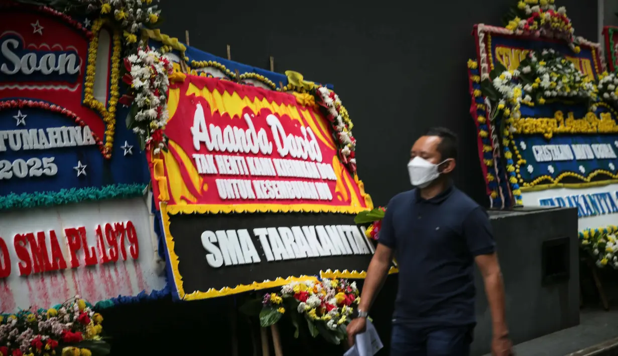 Seorang pria melintas di depan karangan bunga untuk Cristalino David Ozora di Rumah Sakit (RS) Mayapada, Kuningan, Jakarta, Selasa (28/2/2023). Pihak RS Mayapada akan konpers bersama pihak keluarga jam 15.00 WIB," ungkap kuasa hukum David, Syahwat saya dihubungi, Selasa, (28/2/2023). Paman David, Rustam Hatala mengatakan kondisi keponakannya itu dalam dua hari terakhir telah berangsur membaik. (Liputan6.com/Faizal Fanani)