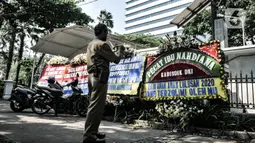 Seorang pegawai mengambil gambar karangan bunga yang terpajang di Balai Kota DKI Jakarta, Senin (6/7/2020). Karangan bunga yang dipasang Relawan PPDB DKI Jakarta 2020 itu sebagai bentuk kekecewaan atas aturan umur serta akreditasi dalam penerimaan siswa baru Jalur Zonasi. (merdeka.com/Iqbal Nugroho)