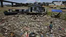 Anak laki-laki berjalan di samping rumah terapung yang terdampar di tempat yang dulunya merupakan tepi sungai Negro, di tengah kekeringan di Manaus, Brasil, Selasa, 26 September 2023. (AP Photo/Edmar Barros)