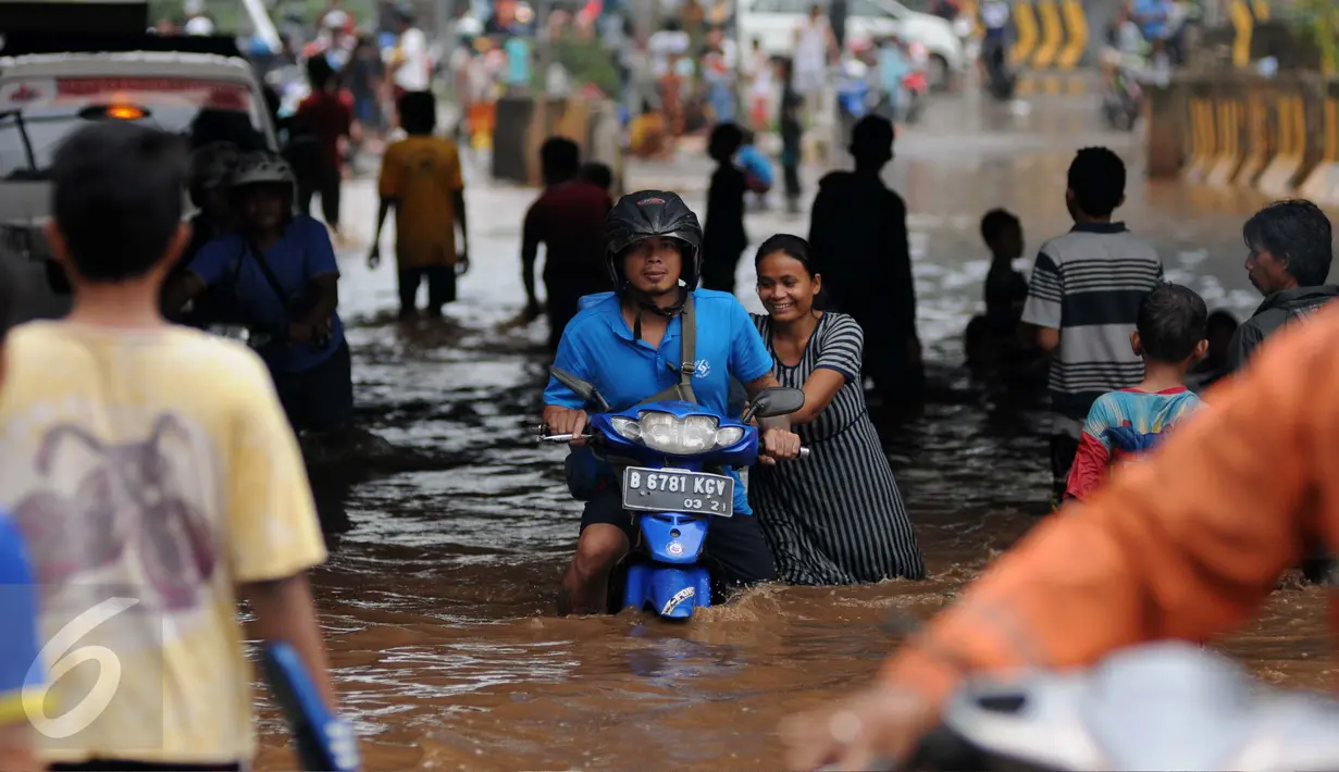 Seorang wanita membantu mendorong motor yang mogok saat berusaha menerobos banjir di Jalan Raya Kalimalang, Caman, Bekasi, Senin (20/2). Akibat banjir tersebut, arus lalu lintas di Kalimalang macet parah. (Liputan6.com/Gempur M Surya)