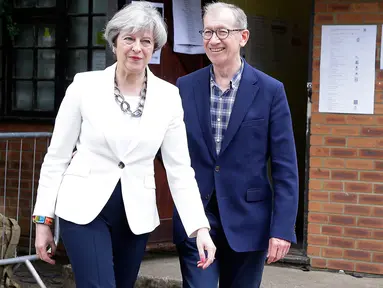 Perdana Menteri (PM) Inggris Theresa May ditemani suaminya, Phillip, meninggalkan TPS Kota Maidenhead, Kamis (8/6). Sebanyak 650 anggota parlemen Westminster akan dipilih, dengan sekitar 46,9 juta orang terdaftar untuk memilih. (AP Photo/Alastair Grant)