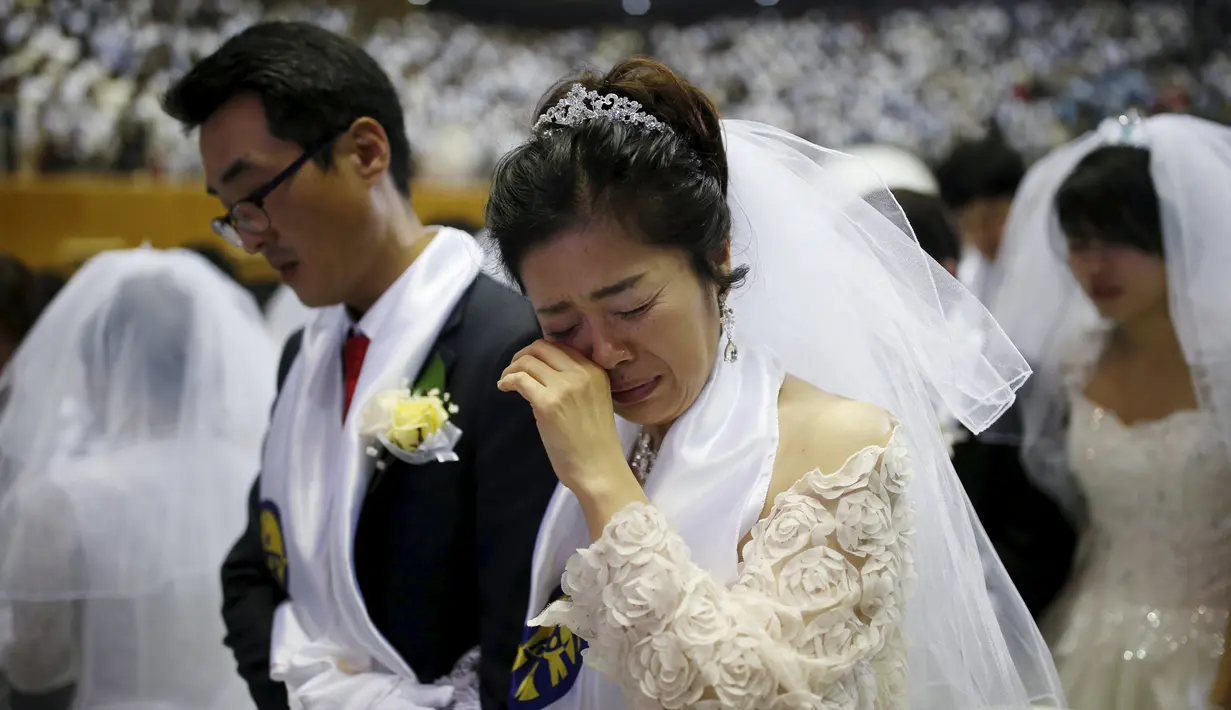 Seorang wanita terharu saat mengikuti pernikahan massal di Gereja Unifikasi Korea Selatan, (20/02). Pernikahan massal di gereja ini telah dimulai pada awal 1960-an yang baru diikuti oleh puluhan pasangan. (REUTERS / Kim Hong - Ji)