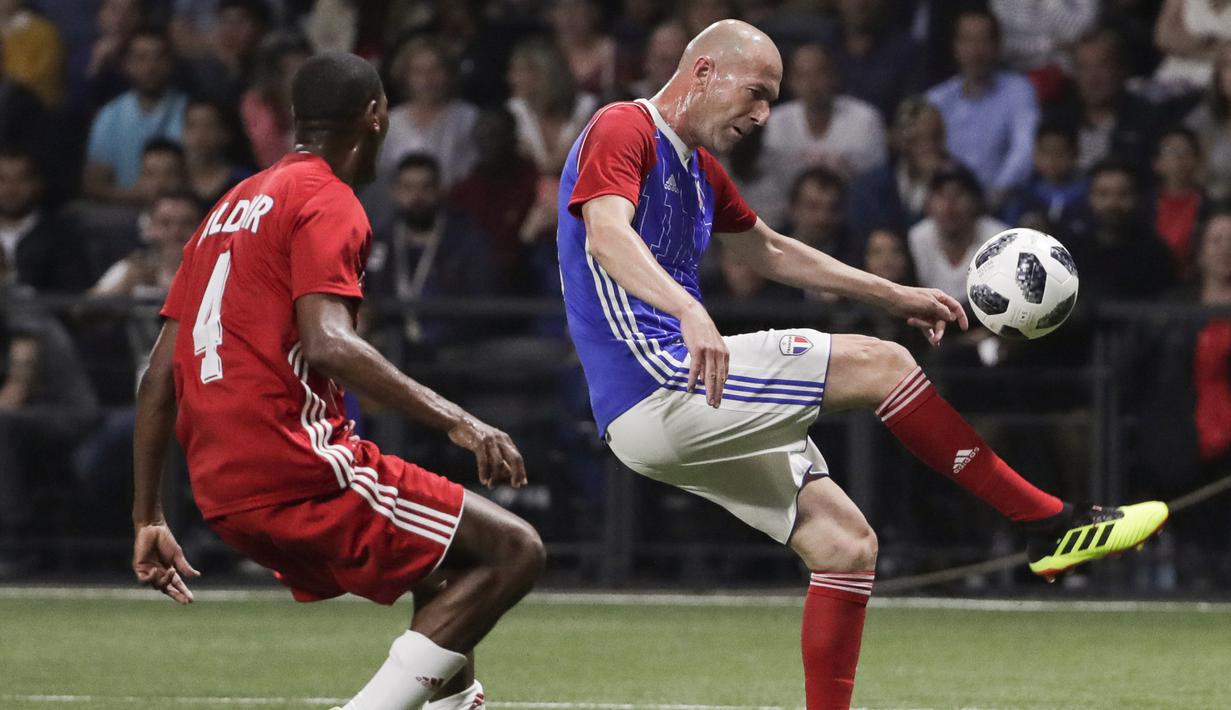 Gelandang Zinedine Zidane mengontrol bola dari kawalan Aldair saat pertandingan tim Prancis 98 dengan tim FIFA 98 di Arena U, Nanterre, Paris (12/6). Pertandingan ini memperingati 20 tahun kemenangan Prancis di Piala Dunia 1998. (AFP Photo/Thomas Samson)