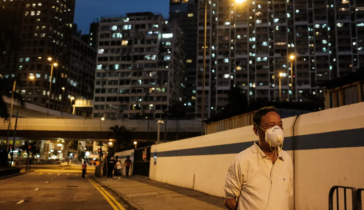 Seorang pria memakai masker berjalan di sepanjang jalan di Hong Kong (21/4/2020). Kepala eksekutif Carrie Lam mengatakan langkah-langkah jarak sosial dan beberapa pembatasan bisnis akan berlanjut selama dua minggu hingga setidaknya 7 Mei. (AFP/Anthony Wallace)