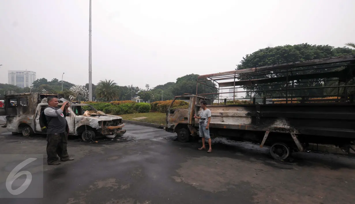 Warga berfoto di depan bangkai mobil aparat yang dibakar demonstran 4 November di kawasan Monas, Jakarta, Sabtu (5/11). Pengunjung menjadikan dua kendaraan milik kepolisian tersebut sebagai objek foto dan melakukan swafoto. (Liputan6.com/Angga Yuniar)