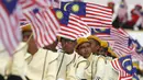 Warga mengikuti parade kemerdekaan sambil mengibarkan bendera Malaysia saat perayaan Hari Kemerdekaan ke-58 di Kuala Lumpur, Senin (31/8/2015).  Perayaan kemerdekaan kali ini dilakukan di tengah desakan mundur kepada PM Najib. (REUTERS/Olivia Harris)