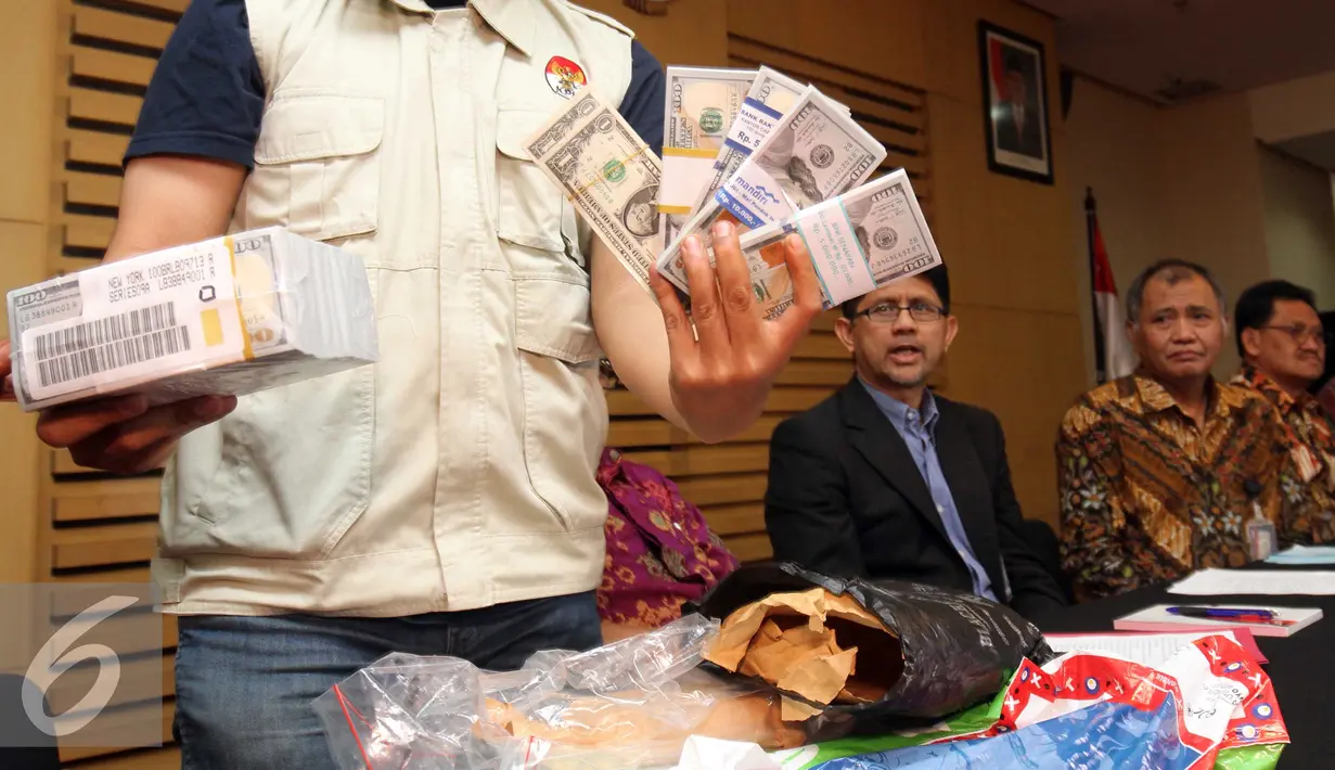 Petugas KPK menunjukkan barang bukti senilai USD 148.835 yang diduga untuk melakukan suap guna menghentikan penanganan kasus PT Brantas di Kejati DKI Jakarta saat konferensi pers di Gedung KPK, Jakarta, Jumat (1/4). (Liputan6.com/Faizal Fanani)