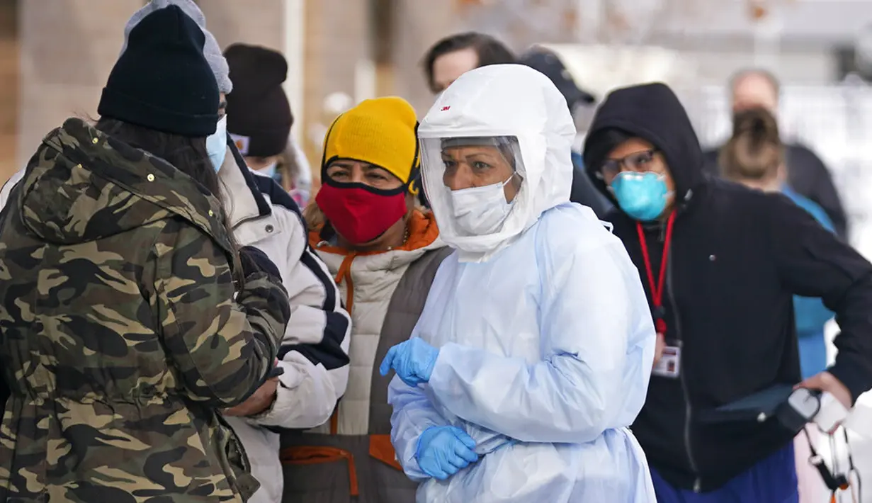 Petugas pengujian COVID-19 Departemen Kesehatan Salt Lake County berjalan melewati antrean warga di luar Departemen Kesehatan Salt Lake County, Salt Lake City, Utah, Amerika Serikat, 28 Desember 2021. Diprediksi, COVID-19 di AS bakal naik hingga 500 ribu kasus dalam sehari. (AP Photo/Rick Bowmer)