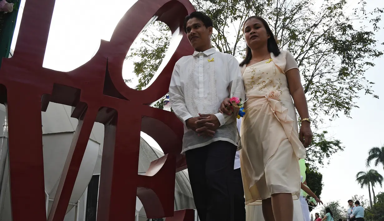Pasangan tiba untuk mengikuti pernikahan massal sebagai bagian dari perayaan Hari Valentine di Manila, Filipina (14/2). Sekitar 200 pasangan dilaporkan ikut serta dalam acara tersebut. (AFP Photo/Ted Aljibe)