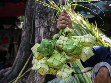 Pedagang menunjukkan cangkang ketupat di kawasan Palmerah, Jakarta, Minggu (18/7/2021). Pemberlakuan PPKM Darurat membuat penjualan cangkang ketupat jelang Idul Adha tahun ini sepi pembeli. (Liputan6.com/Faizal Fanani)