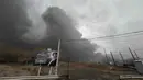 Kementerian perminyakan Iran menyatakan, salah satu depot minyak di Karaj, bagian barat Teheran, juga terkena serangan pada Sabtu 7 Maret 2026 malam. Tampak dalam foto, kepulan asap tebal dari serangan gabungan AS-Israel terhadap fasilitas minyak pada pada Sabtu 7 Maret 2026 malam masih terlihat di langit berawan di belakang papan reklame yang menampilkan mendiang Pemimpin Tertinggi Iran Ali Khamenei di Teheran, Minggu, 8 Maret 2026. (AP Photo/Vahid Salemi)