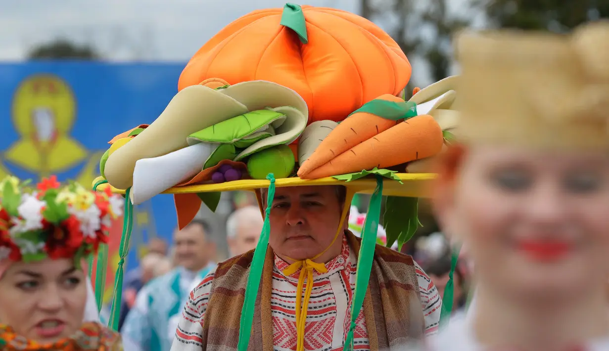 Seorang warga Belarusia memakai baju adat dan topi berhiaskan sayuran saat mengikuti Festival Dozynki di Minsk, Belarusia, Minggu (7/10). Festival ini merupakan bentuk syukur setelah hasil panen yang melimpah. (AP Photo/Sergei Grits)