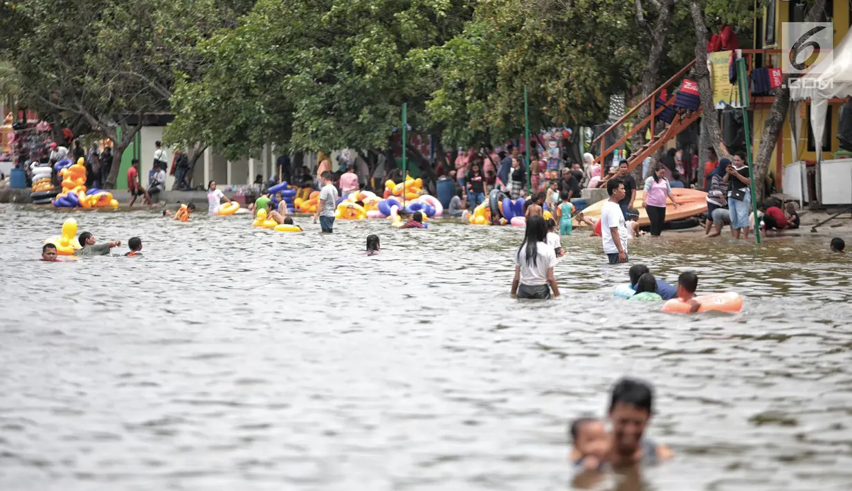 Sejumlah pengunjung bermain air di Beach Pool Ancol, Jakarta, Selasa (25/12). Pasangnya air laut dan cuaca buruk mengakibatkan pantai Ancol sepi pengunjung saat libur Natal 2018. (Liputan6.com/Faizal Fanani)