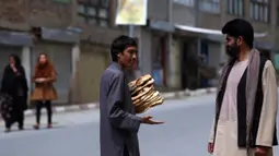 Seorang pria membawa roti gratis dari kota selama lockdown untuk mencegah penyebaran virus corona, pada bulan suci Ramadan di Kabul, Afghanistan (4/5/2020). Muslim di seluruh dunia sedang menjalankan Ramadan, ketika mereka menahan diri dari makan, minum dari subuh hingga senja. (AP/Rahmat Gul)