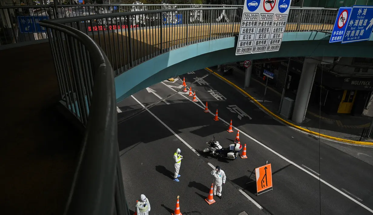 Petugas transit, mengenakan alat pelindung, mengontrol akses ke terowongan ke arah distrik Pudong dalam penguncian sebagai tindakan melawan virus corona Covid-19, di Shanghai (28/3/2022). (AFP/Hector Retamal)