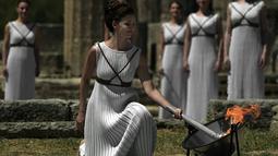 Aktris Yunani, Katerina Lechou, menyalakan api olimpiade dalam suatu upacara di Candi Hera yang terletak di bekas kota tua Olympia, Yunani, Kamis (21/4/2016). Olympia adalah kota dimana olimpiade lahir tahun 776 Sebelum Masehi. (AFP/Aris Messinis)