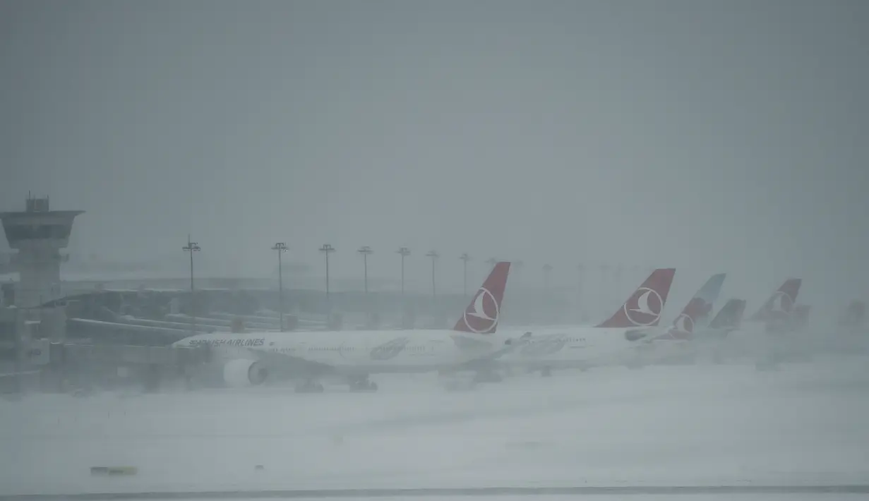 Sejumlah pesawat terparkir di Bandara Ataturk akibat landasan ditutupi salju tebal yang melumpuhkan Kota Istanbul, Turki, Sabtu (7/1). Badai salju dahsyat melumpuhkan aktivitas warga dengan ratusan jadwal penerbangan tertunda. (OZAN KOSE/AFP)