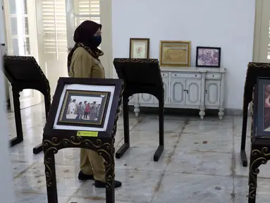 Ibu Endang dari Unit Pengelola Gedung Pertunjukan dan Seni Budaya (UP-GPSB) Dinas Pariwisata dan Budaya Pemprov DKI Jakarta menunjukkan beberapa koleksi foto-foto lawas seniman betawi, Benyamin Suaeb di Gedung Taman Benyamin Suaeb, Jakarta, Selasa (23/6/2020). (Liputan6.com/Helmi Fithriansyah)