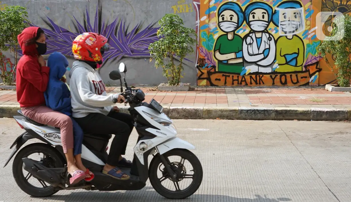 Pengendara sepeda motor melintas di depan mural bertema pandemi virus corona COVID-19 di kawasan Sunter, Jakarta, Selasa (2/6/2020). Mural tersebut dibuat sebagai wujud dukungan terhadap tenaga medis serta masyarakat agar tetap semangat menghadapi pandemi COVID-19. (Liputan6.com/Immanuel Antonius)