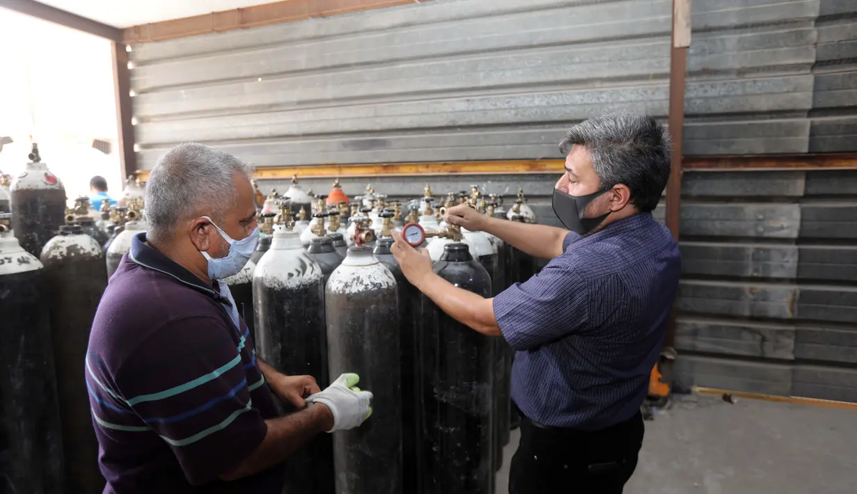 Orang-orang memeriksa tekanan oksigen di tempat pengisian ulang oksigen di Baghdad, Irak (7/7/2020). Pabrik pengisian oksigen milik pemerintah di Irak meningkatkan pengisian tabung oksigen dan gas cairnya untuk memenuhi permintaan rumah sakit di tengah terus bertambahnya infeksi COVID-19. (Xinhua)
