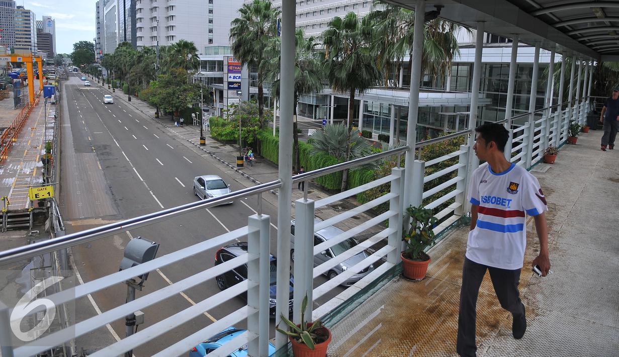 Seorang pria melintas di jembatan penyebraan orang di Kawasan Bundaran HI, Jakarta, Rabu (15/2). Sebagian besar perkantoran di Jakarta libur karena pemerintah telah menetapkan Rabu ini sebagai hari libur nasional. (Liputan6.com/Angga Yuniar)