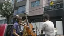 Warga (kanan) menyaksikan band Maroto Jazz Trio yang terdiri dari Diego Maroto pada Saxophone, Jorge Molina pada double bass, dan Edy Vega pada drum tampil dari atas sebuah van melewati kawasan Mexico City, Meksiko, 29 Agustus 2020. (RODRIGO ARANGUA/AFP)