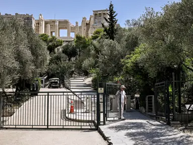 Seorang karyawan menutup gerbang akses ke situs arkeologi Acropolis di Athena pada 14 Juli 2023. (AFP/Spyros Bakalis)