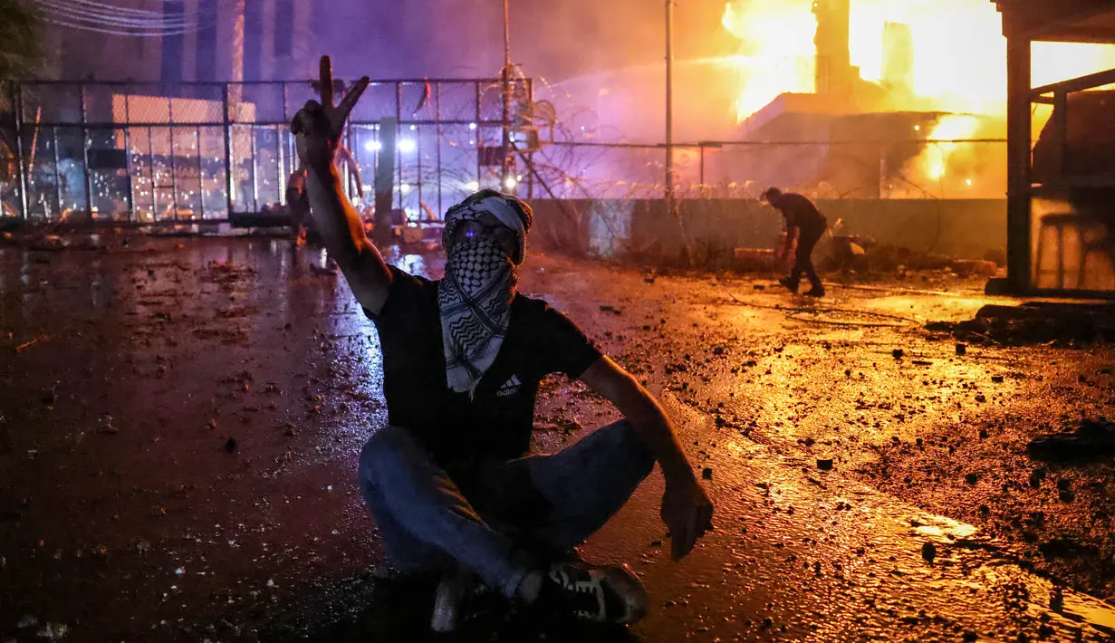 Seorang pengunjuk rasa Lebanon mengacungkan tanda untuk kemenangan saat bentrokan dengan pasukan keamanan dalam sebuah demonstrasi untuk menunjukkan solidaritas kepada warga Gaza di Awkar, sebelah timur Beirut. (JOSEPH EID/AFP)