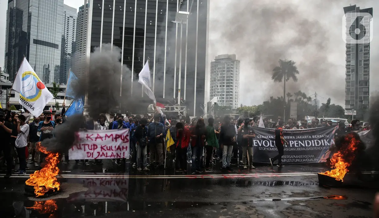 Massa yang tergabung dalam Gerakan Mahasiswa Jakarta Bersatu membakar ban saat unjuk rasa di depan gedung Kementerian Pendidikan dan Kebudayaan, Jakarta, Kamis (2/7/2020). Mereka menuntut adanya keringanan uang tunggal kuliah (UKT) sebesar 50 persen di tengah pandemi. (Liputan6.com/Faizal Fanani)