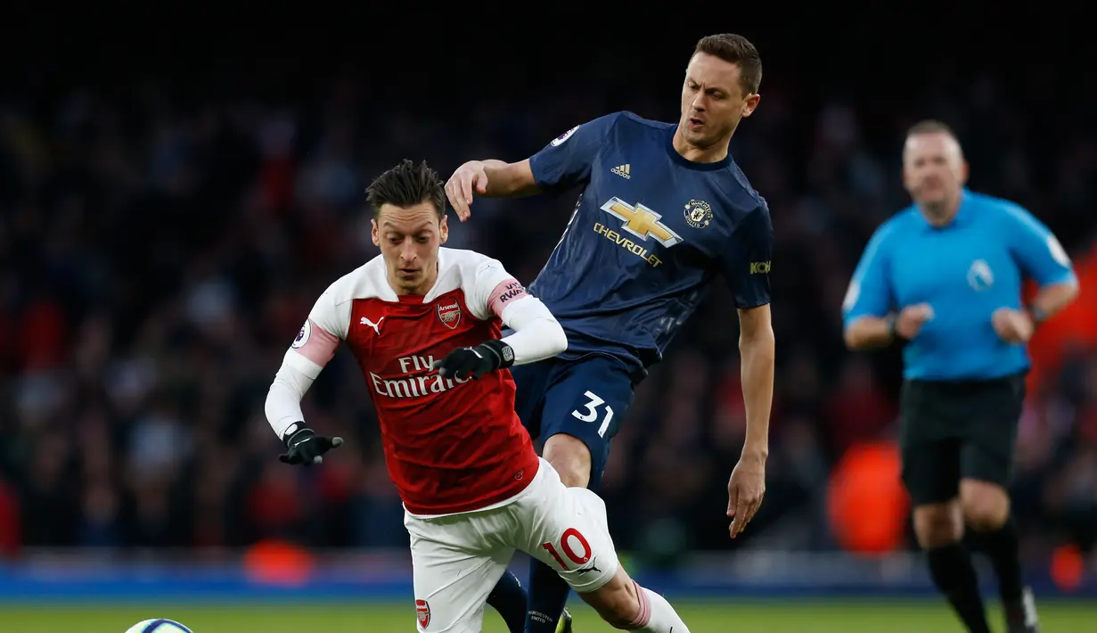 Gelandang Arsenal, Mesut Ozil dihentikan Nemanja Matic pada laga lanjutan Premier League yang berlangsung di Stadion Emirates, London, Minggu (10/3). Arsenal menang 2-0 atas Man United. (AFP/Ben Stansall)