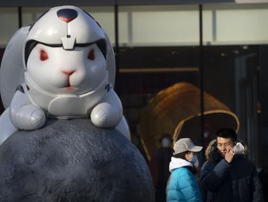 Seorang pria melepas masker saat berfoto dengan patung memperingati Tahun Kelinci di pusat perbelanjaan pada hari terakhir minggu liburan Tahun Baru Imlek di Beijing, Jumat, 27 Januari 2023. (AP/Mark Schiefelbein)