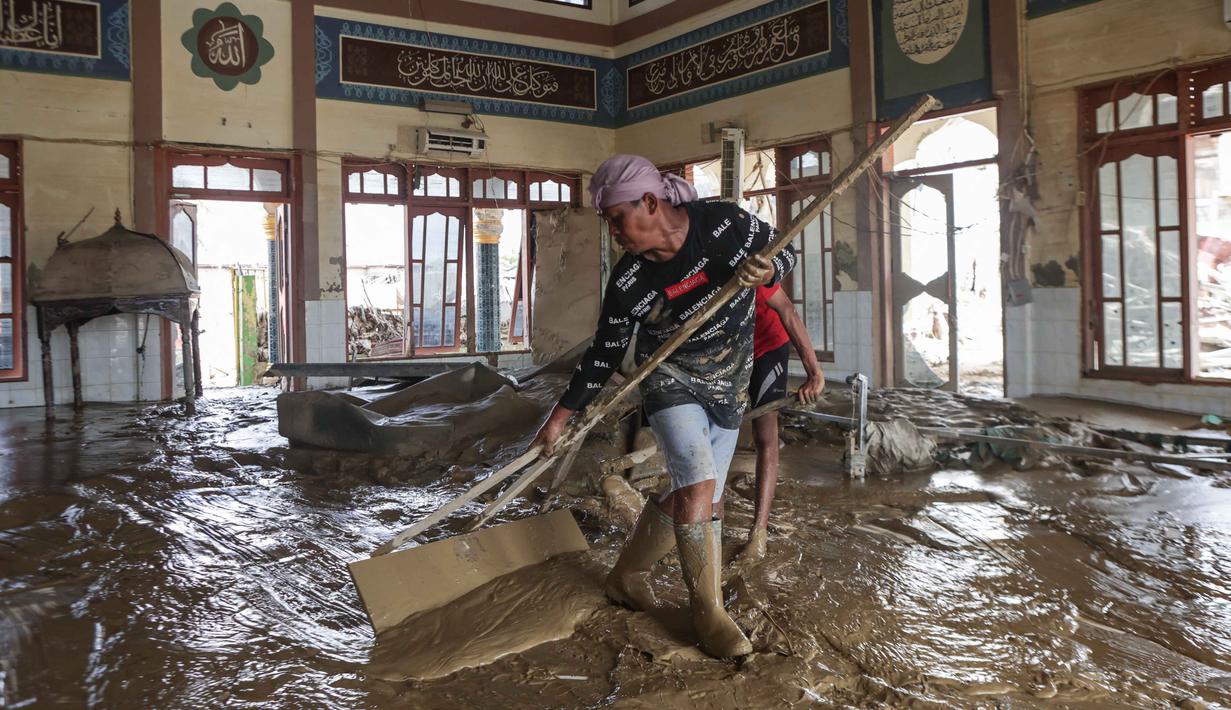 Meski demikian, sebagian warga mulai membersihkan lumpur di pemukiman dan fasilitas umum yang selamat dari terjangan banjir bandang dengan menggunakan alat seadanya. Tampak dalam foto, warga membersihkan lumpur di dalam masjid setelah banjir bandang di desa Lintang Bawah, Aceh Tamiang, Sumatera Utara, pada Kamis 11 Desember 2025. (Aditya Aji/AFP)