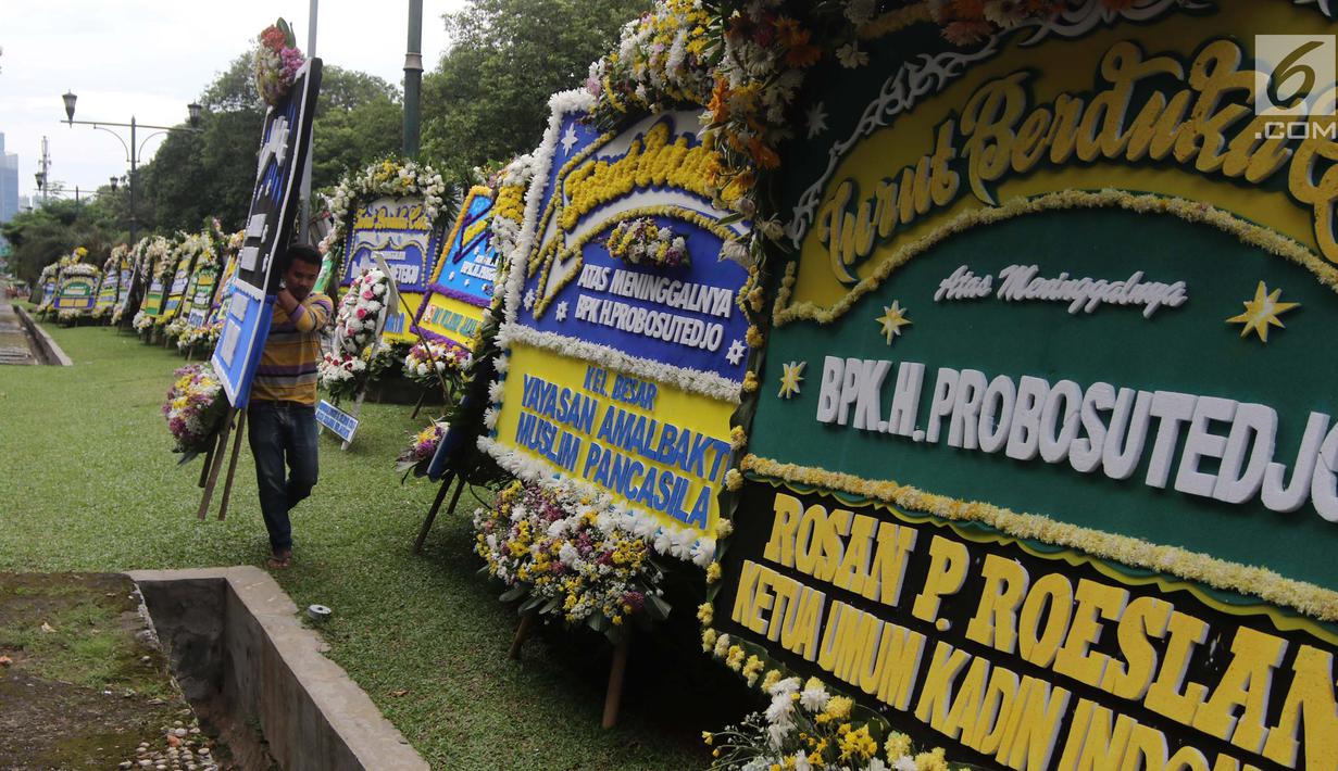 Pekerja membawa karangan bunga ucapan duka cita untuk Probosutedjo yang dipajang di Jalan Diponegoro, Jakarta, Senin (26/3). Probosutedjo meninggal dunia di RSCM Kencana Jakarta Pusat. (Liputan6.com/Arya Manggala)