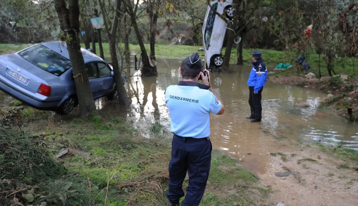 Para petugas sedang mengevakuasi mobil-mobil yang terkena serangan banjir bandang, Grabels, Prancis, Selasa (7/10/2014) (AFP PHOTO/Sylvain THOMAS)