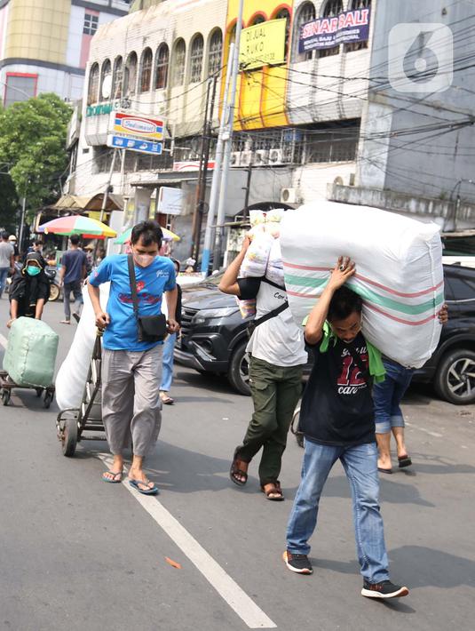 Sejumlah porter saat memanggul pakaian jadi yang di kemas di karung di Kawasan Tanah Abang, Jakarta, Senin (11/10/2021). Menurunnya level PPKM jakarta menjadi level 3 membawa berkah bagi para kuli panggung dikarenakan geliat pasar tersebut kembali berjalan. (Liputan6.com/Angga Yuniar)