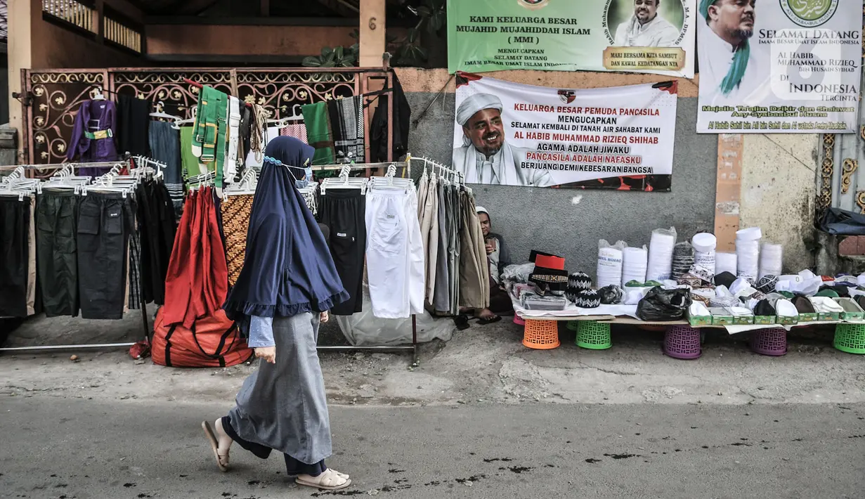 Warga melintas di lapak pedagang atribut FPI di Jalan Petamburan III, Jakarta, Senin (9/11/2020). Jelang kedatangan Imam Besar FPI Habib Rizieq Shihab, warga dan anggota FPI dari berbagai daerah mulai mempersiapkan penyambutan dengan atribut, poster, dan baliho. (merdeka.com/Iqbal S. Nugroho)