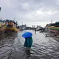 Nelayan melintasi banjir rob saat cuaca ekstrem di Pelabuhan Muara Baru, Penjaringan, Jakarta Utara, Rabu (28/12/2022). Banjir ROB, hujan deras dan  cuaca buruk melanda kawasan Pelabuhan Muara Baru saat siang menjelang sore hari. (Liputan6.com/Johan Tallo)