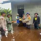 Kapolsek Siak Kecil Ipda Eko Wahyu bersama personel dan TNI serta aparatur desa menyerahkan bantuan sembako kepada korban bencana banjir. (Liputan6.com/M Syukur)