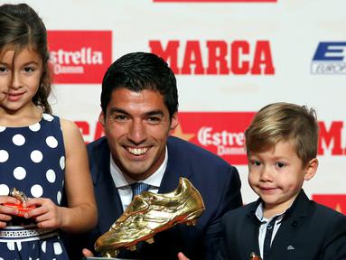 Penyerang Barcelona, Luis Suarez bersama kedua anaknya Delfina dan Benjamin, berpose dengan trofi Sepatu Emas Eropa 2016 selama penghargaan Golden Shoe atau sepatu emas untuk tahun 2016 di Barcelona, Spanyol (20/10). (REUTERS/Albert Gea)
